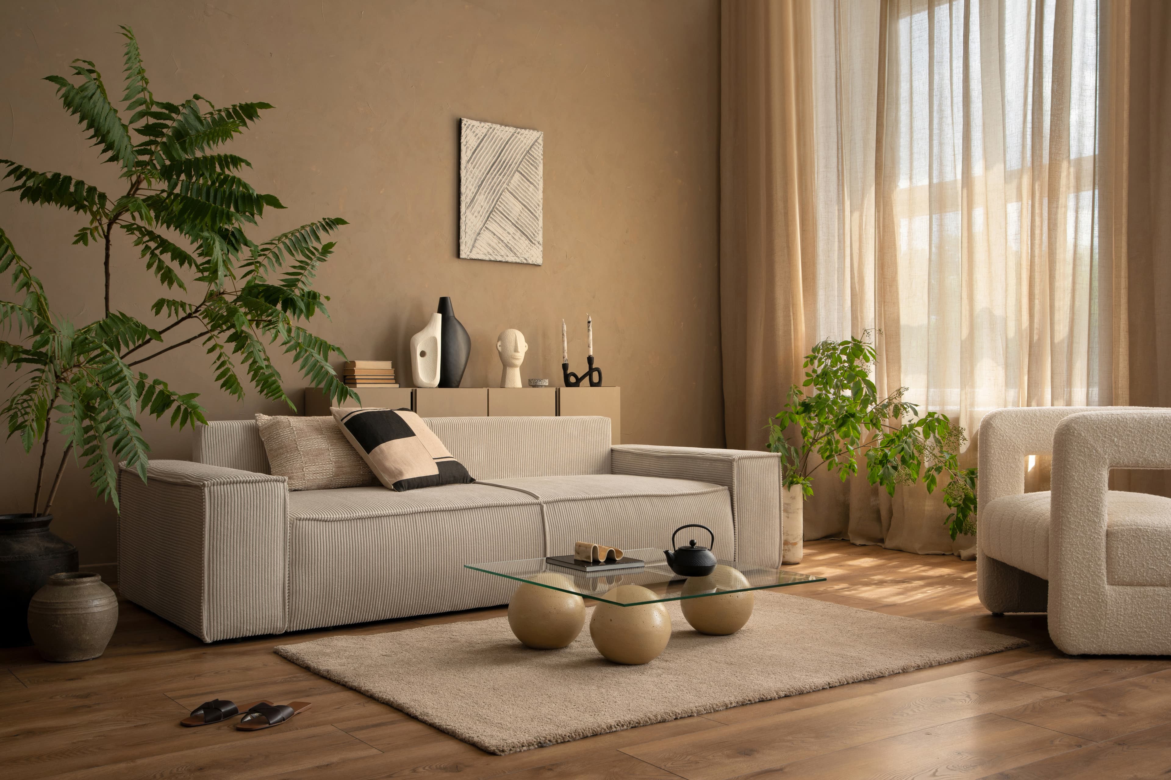 A warm, textured living room — neutral corduroy sofa, linen curtains, bouclé armchair